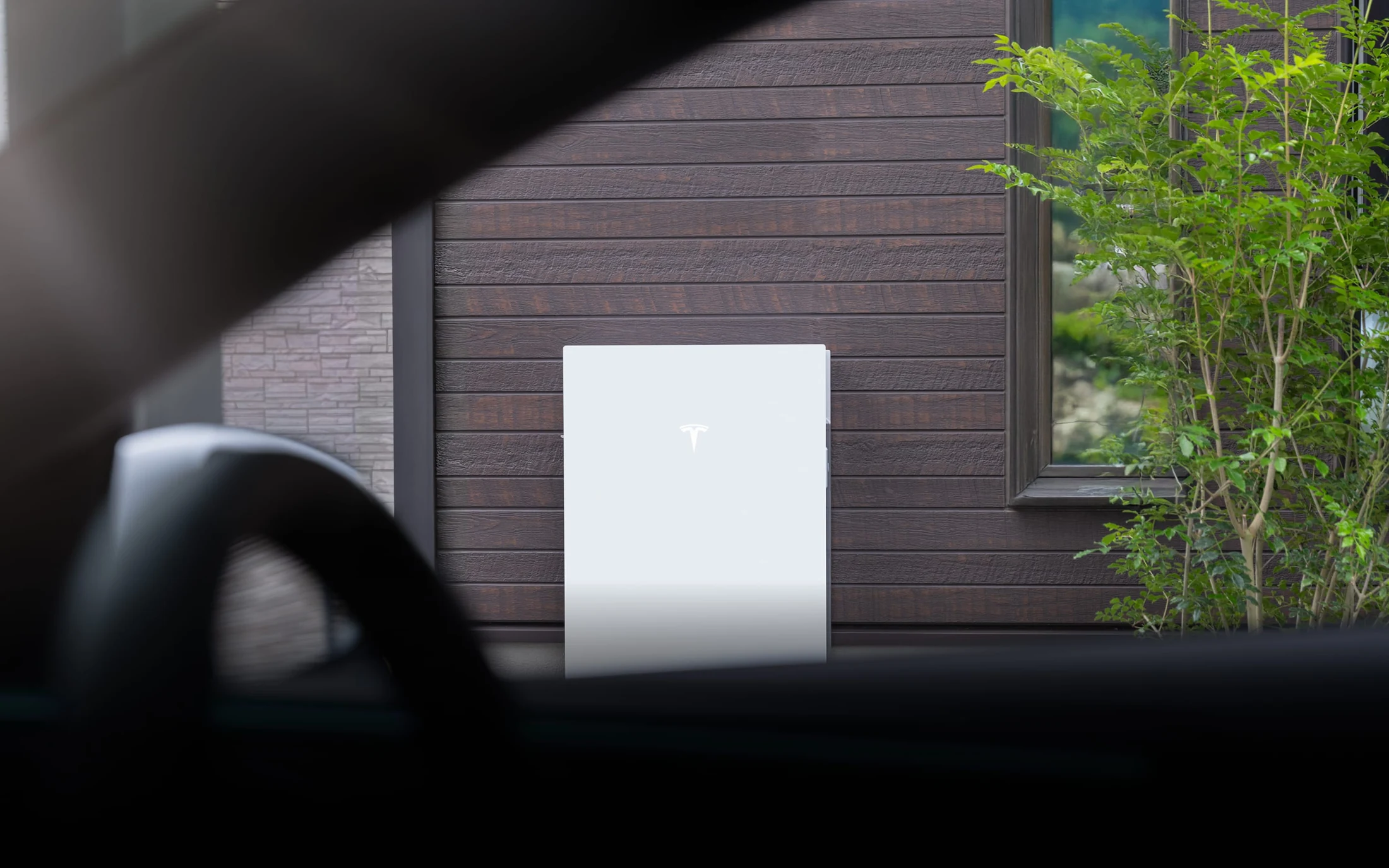 車内から見た、住宅の外壁のTesla Powerwall 3。メーカー公式の製品イメージ